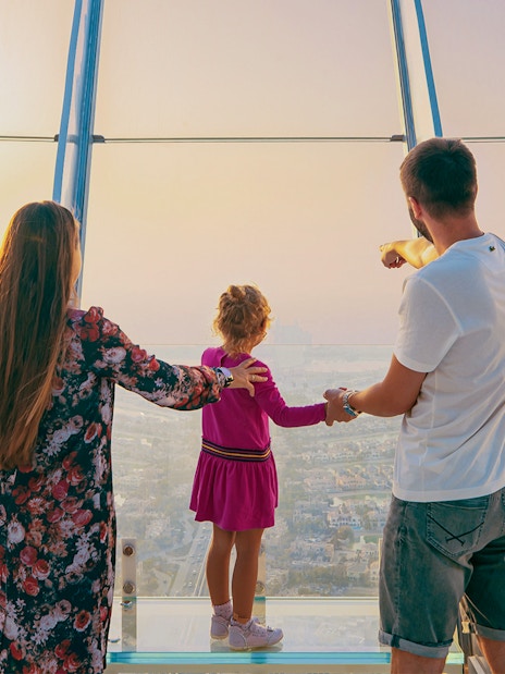 Family enjoying panoramic view of Palm Jumeirah from Dubai Frame observation deck.