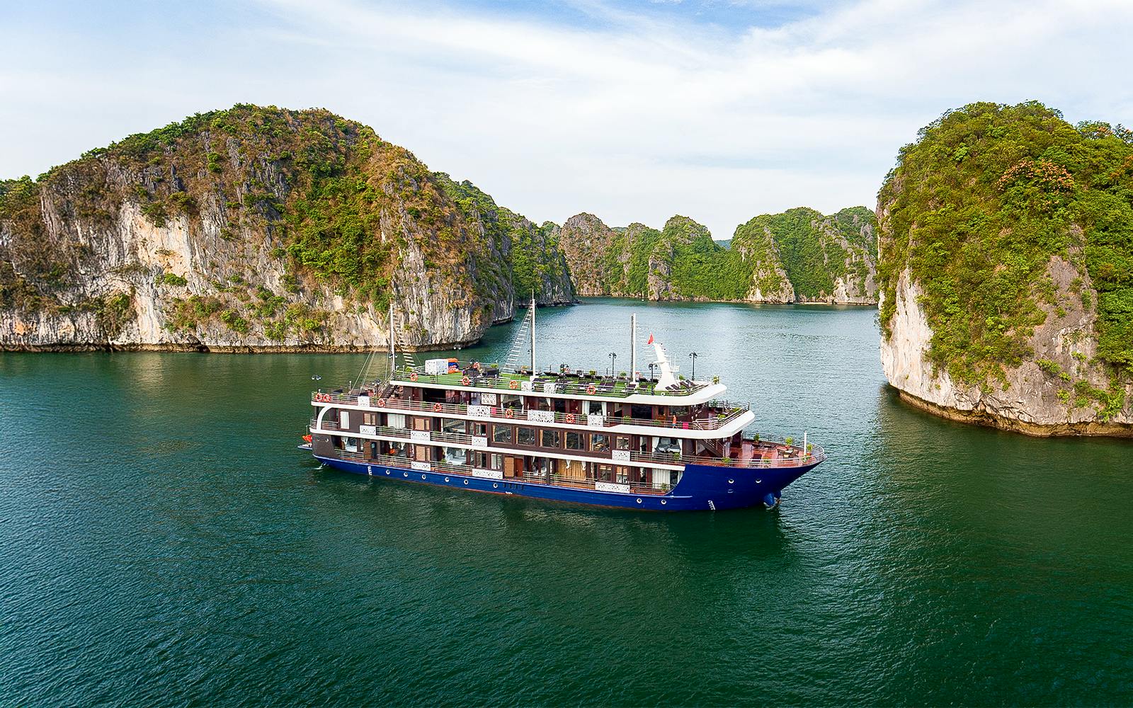 Cruise ship sailing through Lan Ha Bay with limestone karsts in the background.