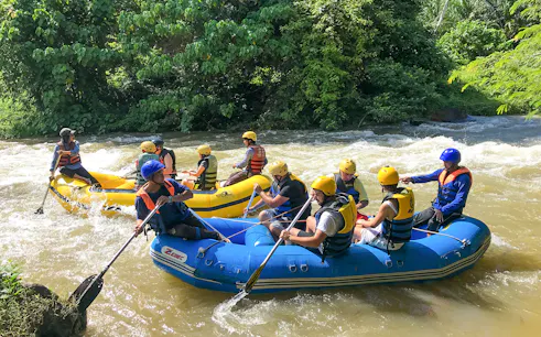 Rafting adventure on a river in Phuket with participants in helmets and life jackets.