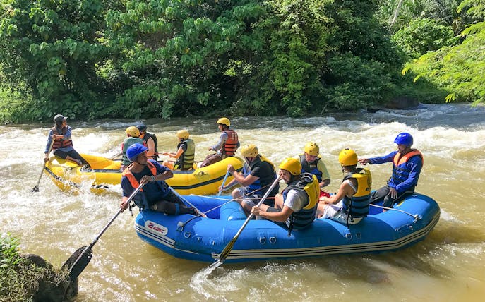 Rafting adventure on a river in Phuket with participants in helmets and life jackets.