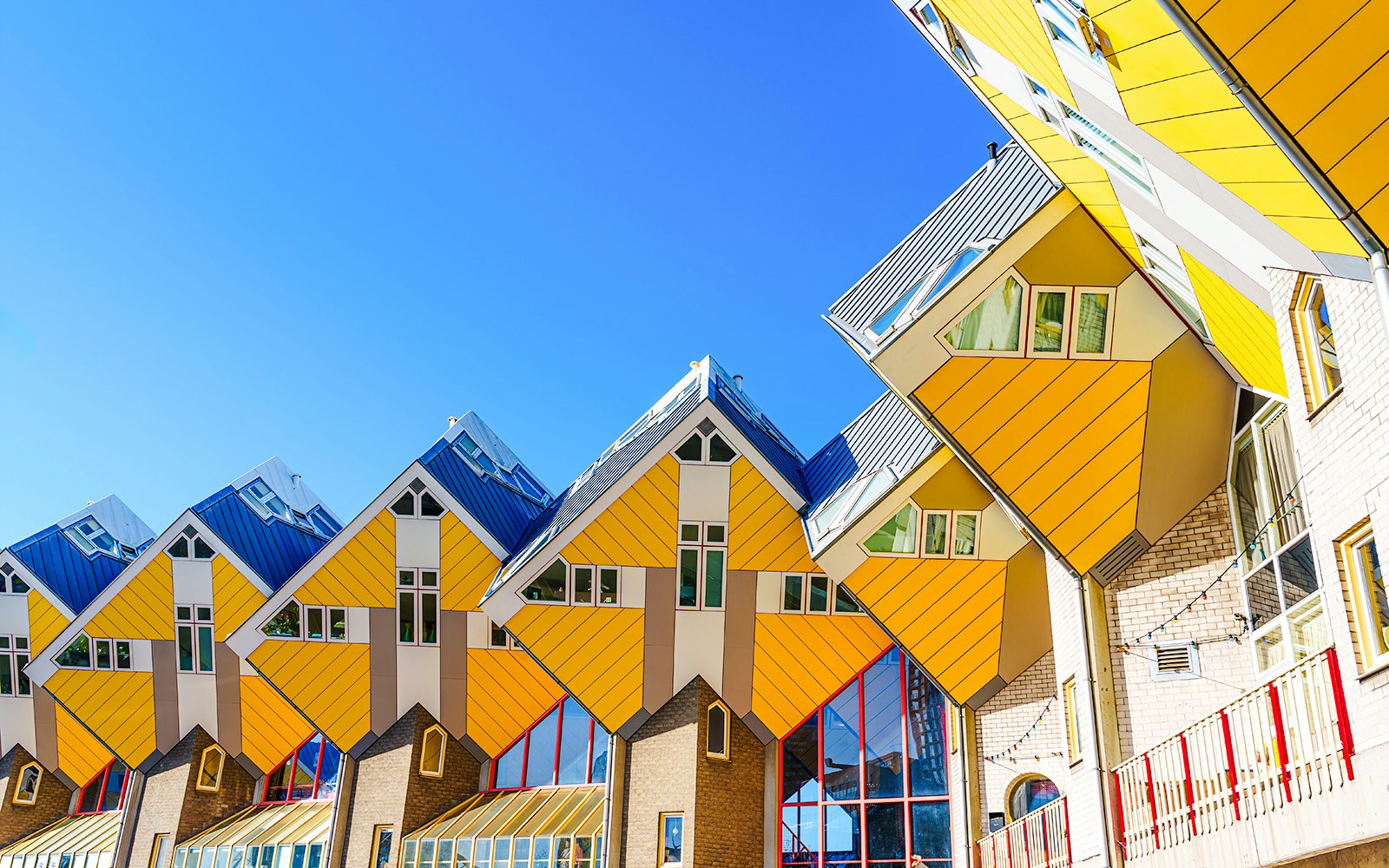 Cube houses in Rotterdam with yellow and white geometric design against a clear blue sky.