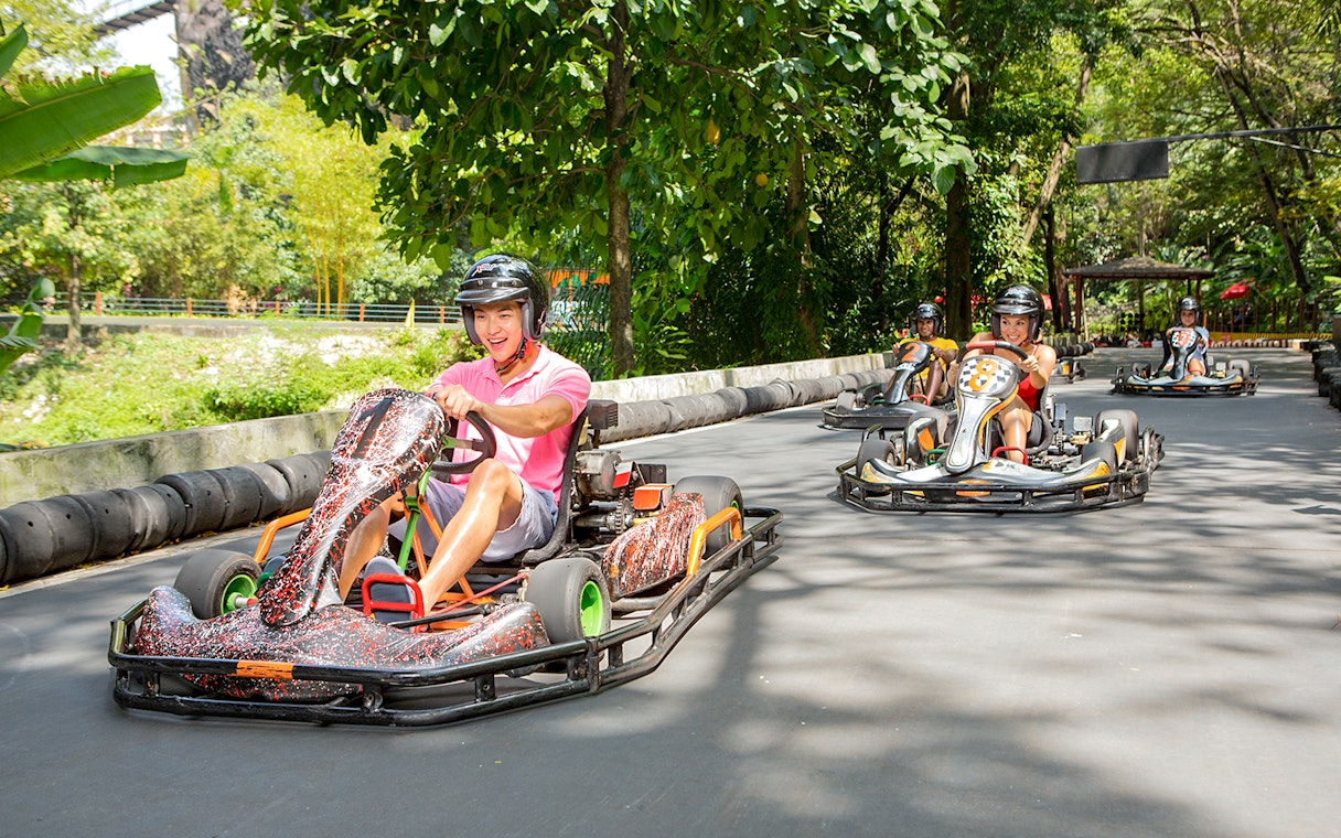 Go karting track at Sunway Lagoon theme park with racers in helmets.
