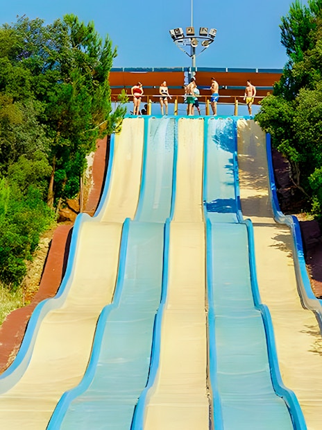 Water slides at Aquopolis Villanueva de la Cañada surrounded by trees.