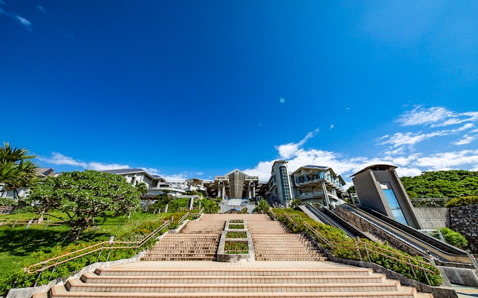 Churaumi Aquarium entrance with stairs and escalators under a clear blue sky.
