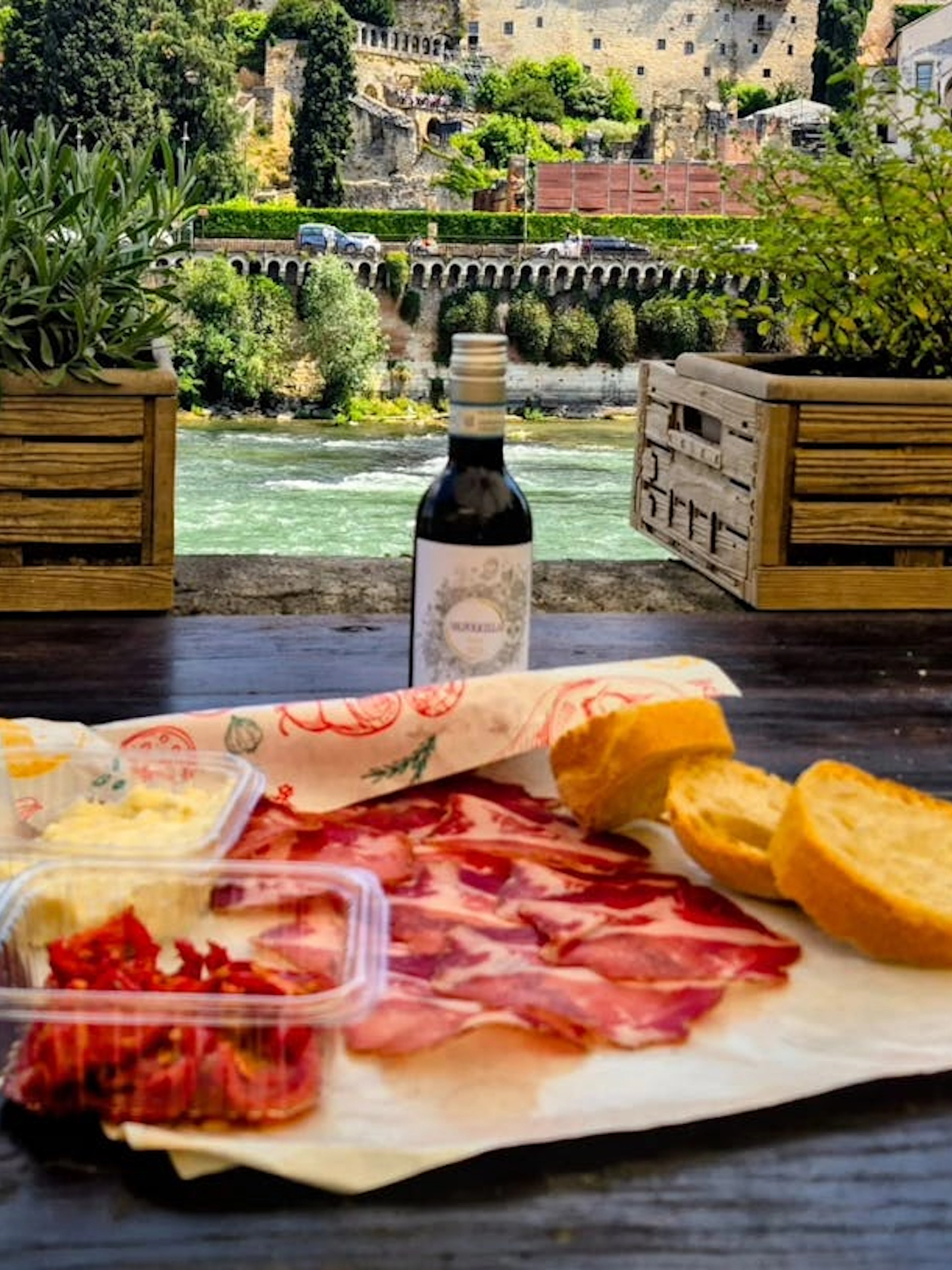 Local meats and wine on a table overlooking Verona's historic architecture.