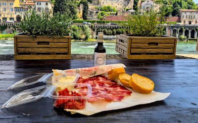 Local meats and wine on a table overlooking Verona's historic architecture.
