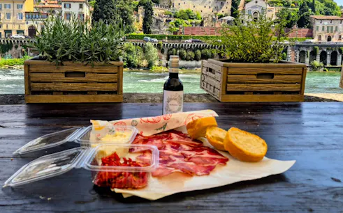 Local meats and wine on a table overlooking Verona's historic architecture.