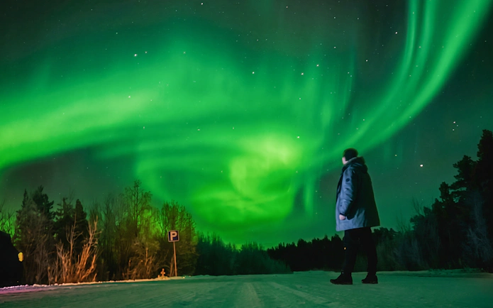 Person observing Northern Lights in Rovaniemi with a photography guide.
