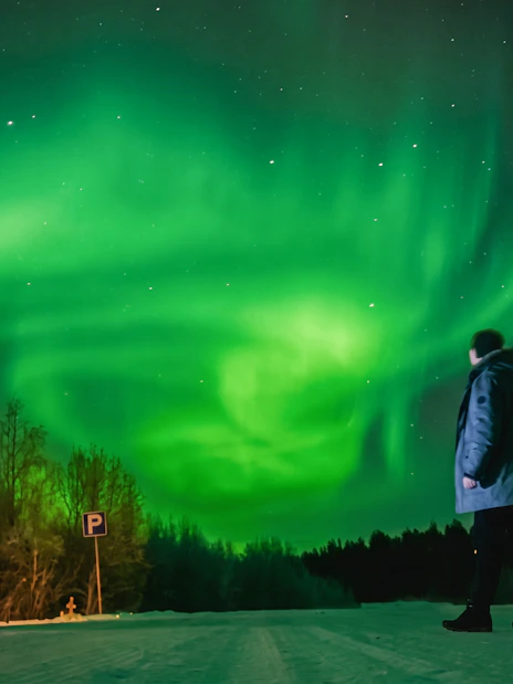 Person observing Northern Lights in Rovaniemi with a photography guide.