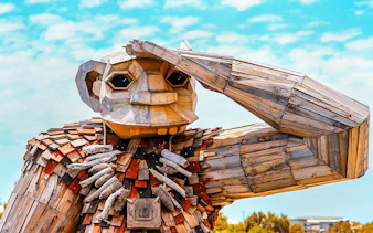 Wooden giant sculpture with hand raised, part of Giant & Dolphin Sightseeing Cruise.