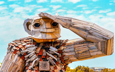 Wooden giant sculpture with hand raised, part of Giant & Dolphin Sightseeing Cruise.