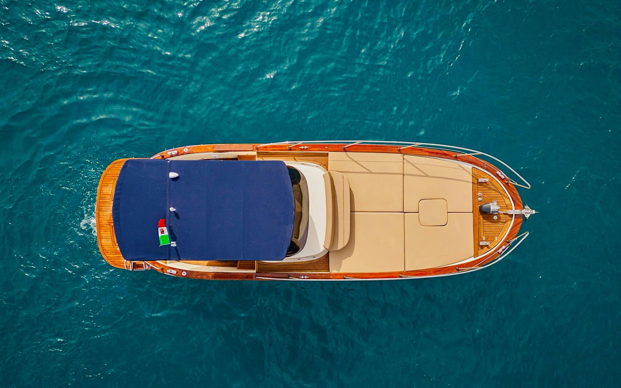 Aerial view of a boat cruising on the Amalfi Coast's blue waters.
