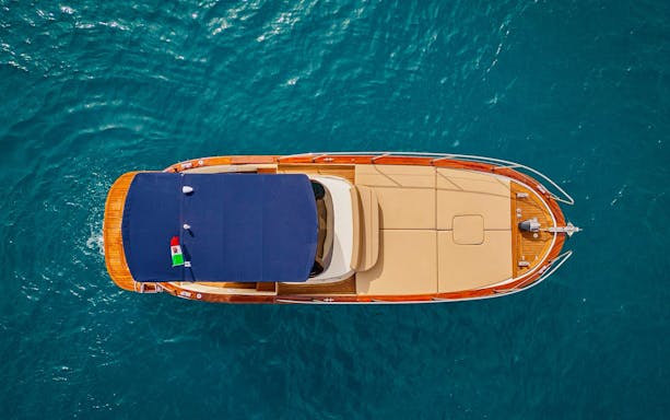 Aerial view of a boat cruising on the Amalfi Coast's blue waters.