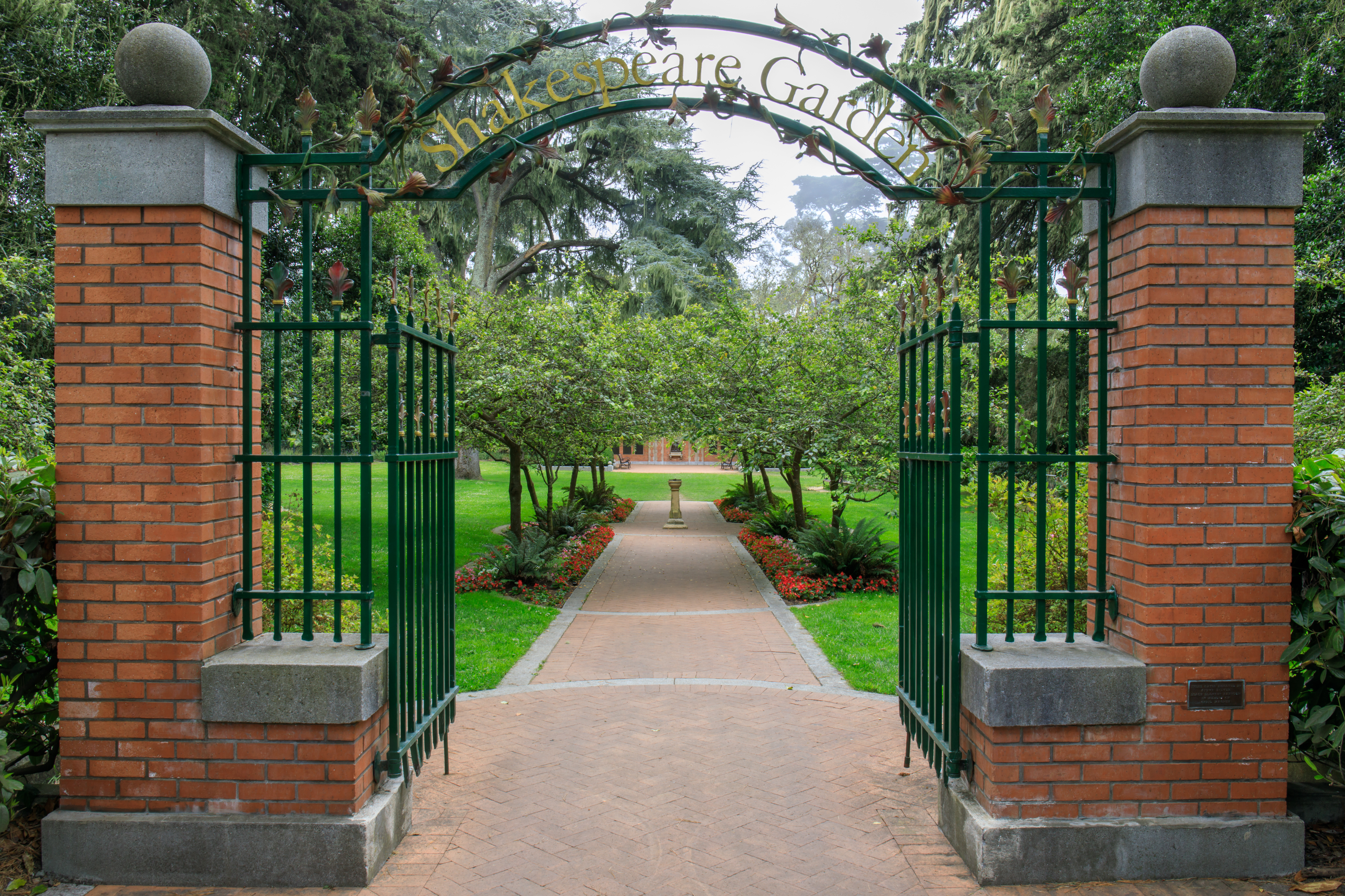 Entrance to Shakespeare Garden with brick pillars and lush greenery.