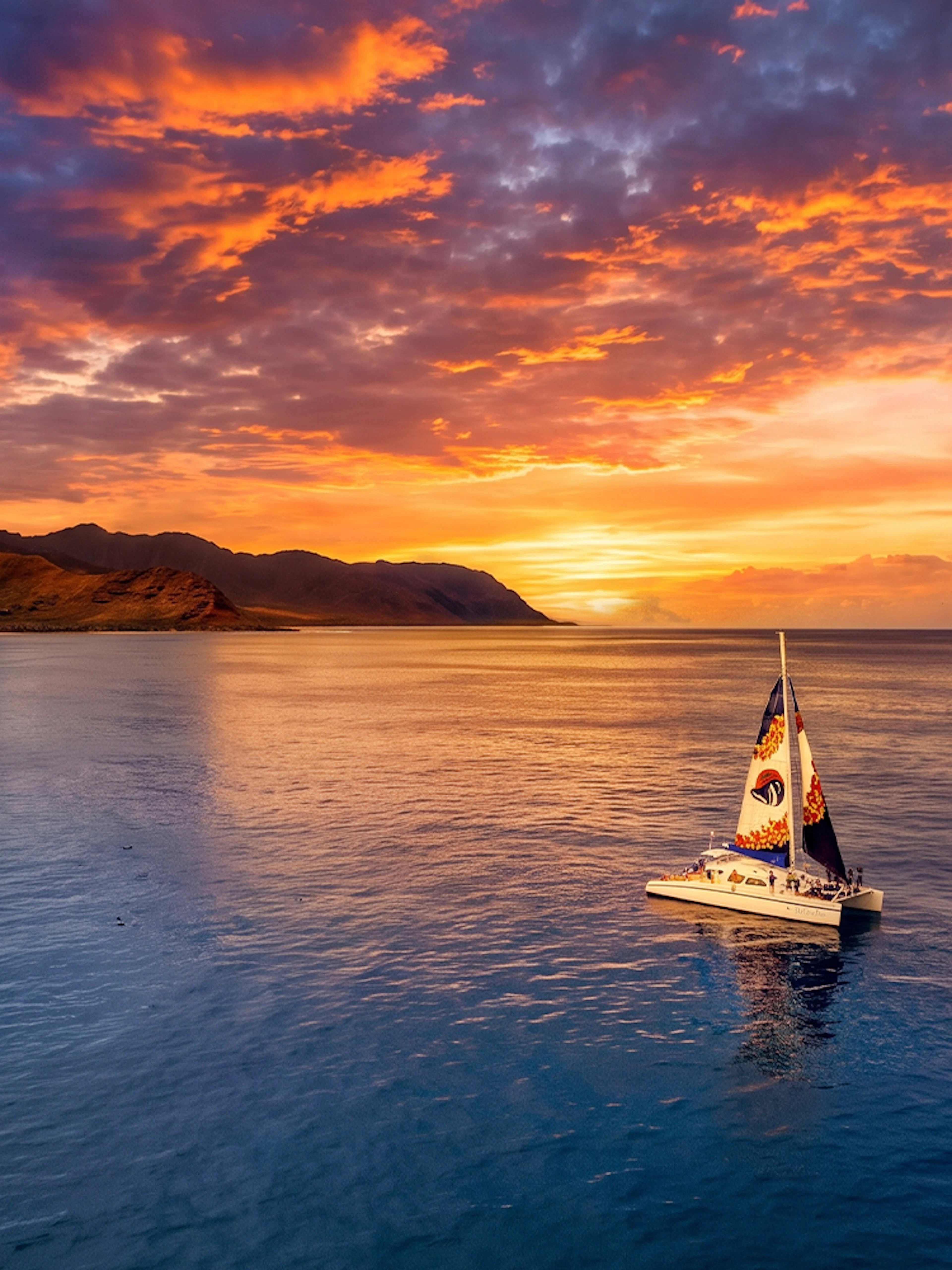 Catamaran sailing at sunset off the coast of West Oahu, Hawaii.