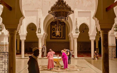 Visitors exploring the courtyard of a madrasa in Fes, Morocco.