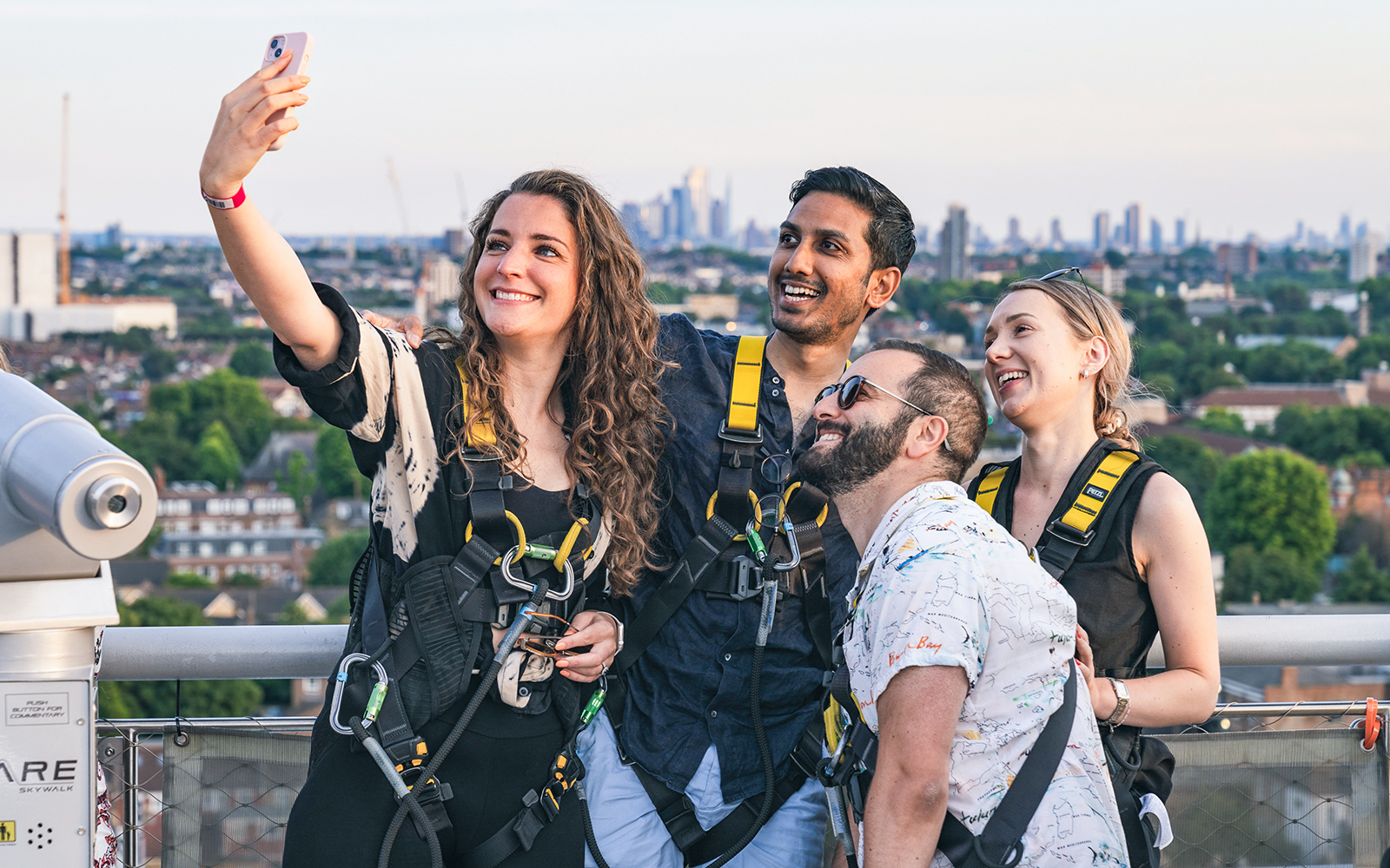 Group taking a selfie on The Dare Skywalk with city skyline in the background.
