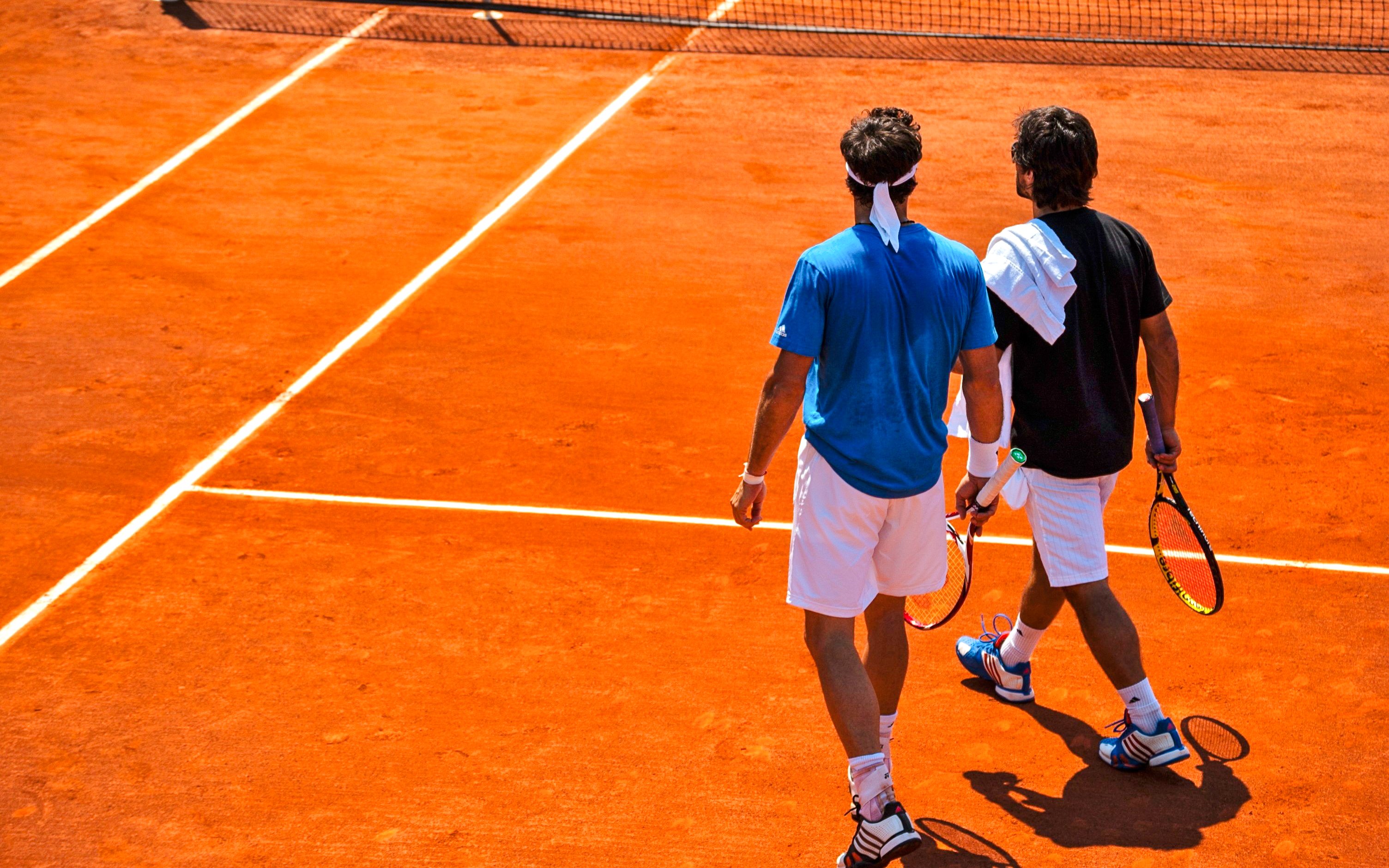 Tennis players walking on clay court at Roland-Garros Stadium.