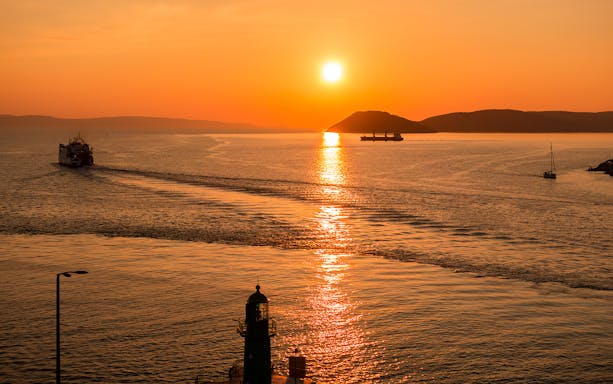 Sunset view of Split Riviera with boats and lighthouse during a panoramic cruise.