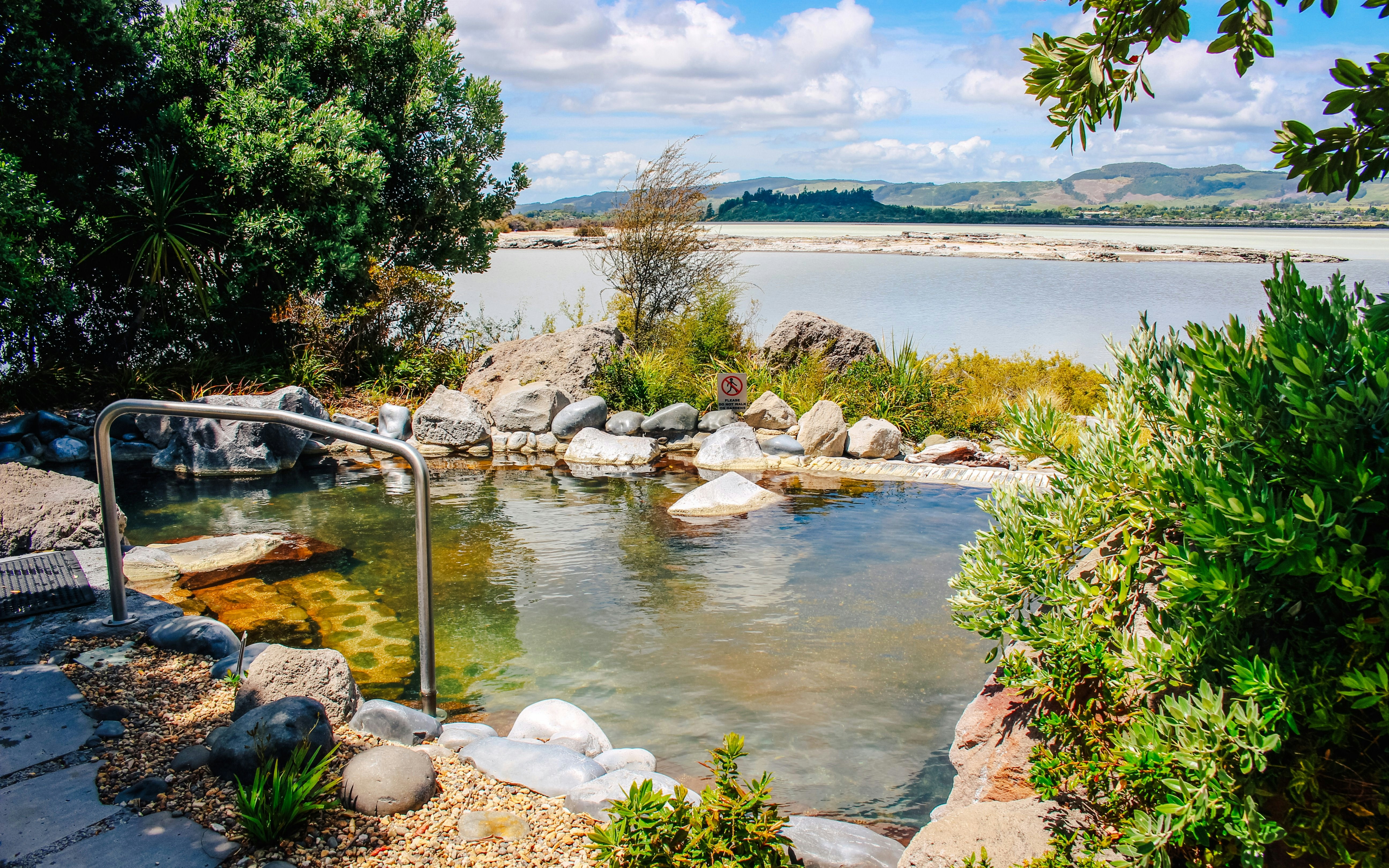 Thermal pool surrounded by rocks and greenery at Polynesian Spa, New Zealand.