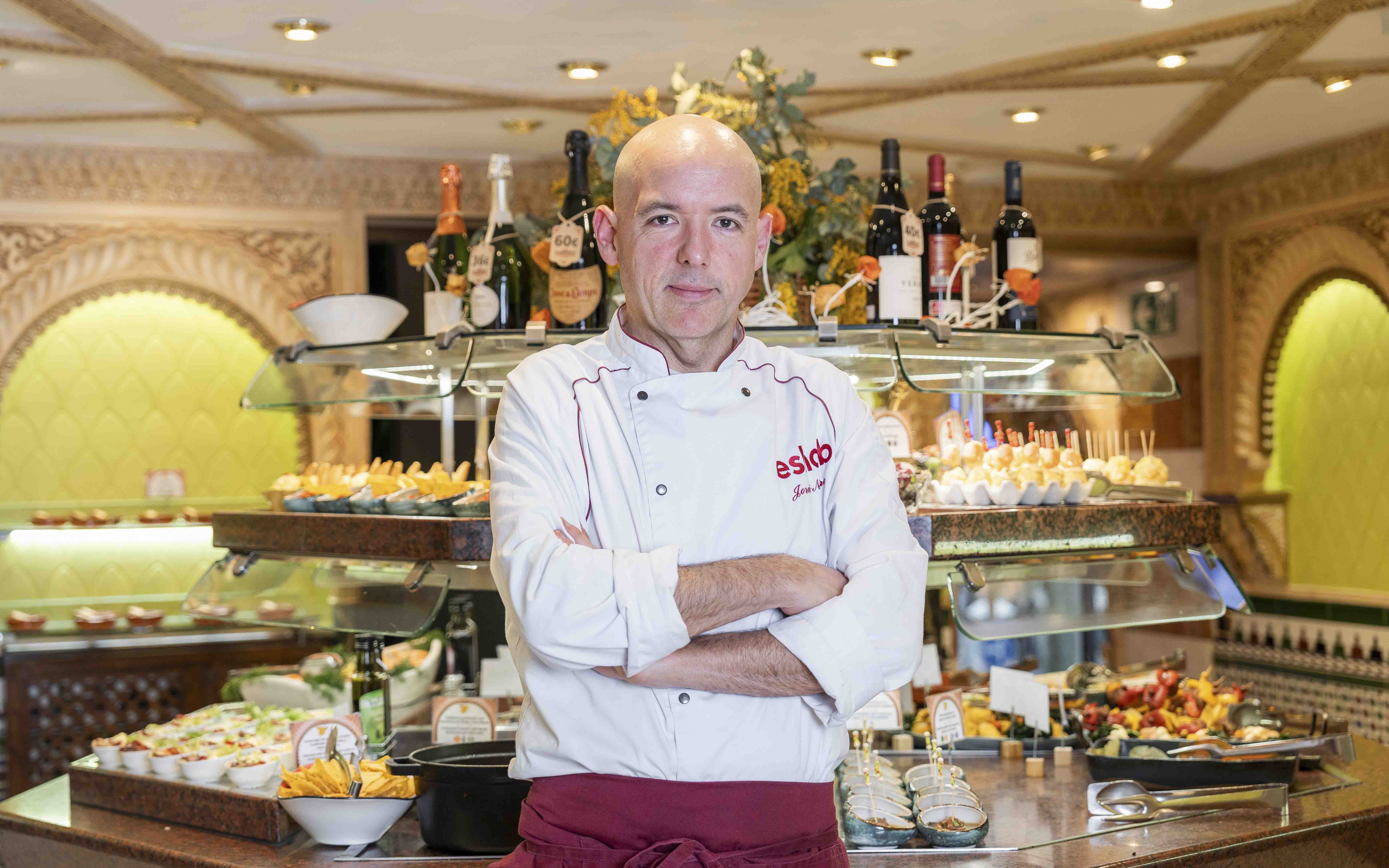 Chef at Tablao Cordobes standing in front of a tapas display in Barcelona.