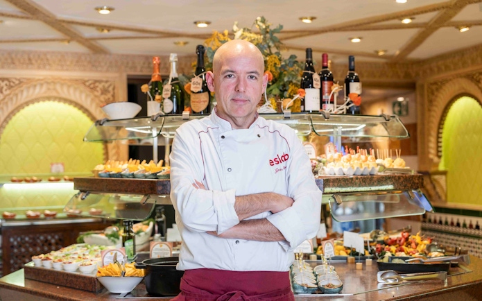 Chef at Tablao Cordobes standing in front of a tapas display in Barcelona.