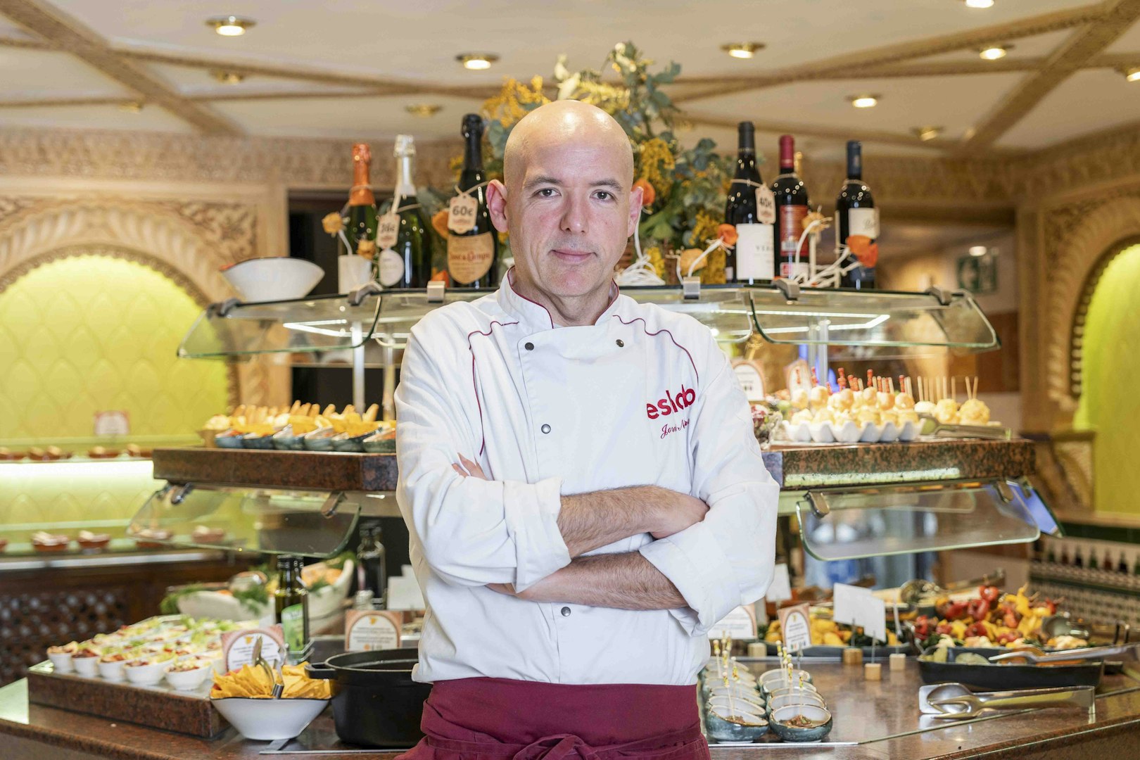 Chef at Tablao Cordobes standing in front of a tapas display in Barcelona.