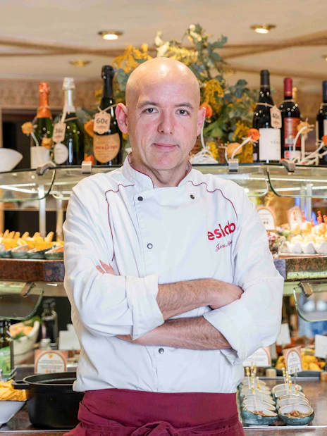 Chef at Tablao Cordobes standing in front of a tapas display in Barcelona.