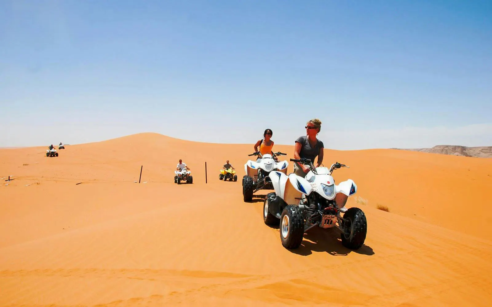 People riding quad bikes on sand dunes during a Dubai desert safari.