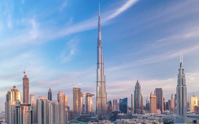 Burj Khalifa towering over Dubai skyline at sunset.