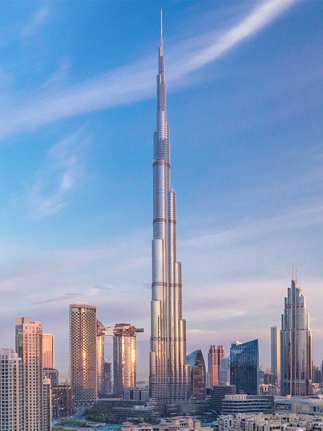 Burj Khalifa towering over Dubai skyline at sunset.