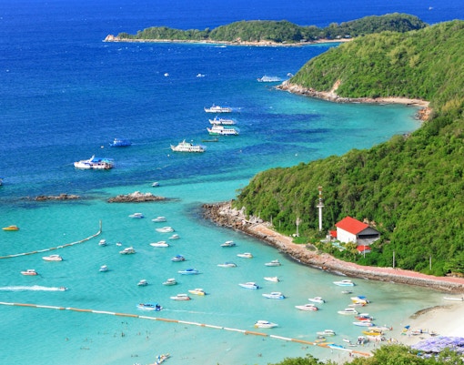 Tourists enjoying a sunny day on the sandy beach of Koh Larn Island, Pattaya, with clear blue waters.