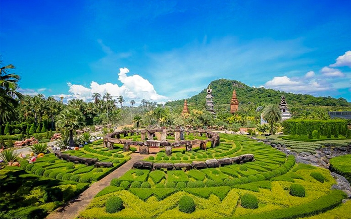 Nong Nooch Tropical Garden with manicured hedges and traditional Thai structures in Pattaya, Thailand.