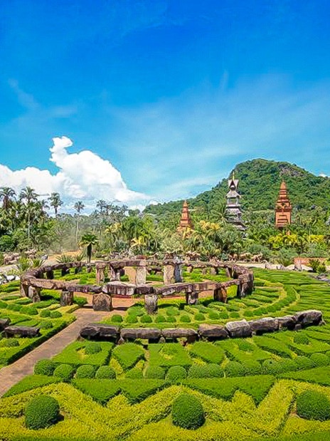 Nong Nooch Tropical Garden with manicured hedges and traditional Thai structures in Pattaya, Thailand.