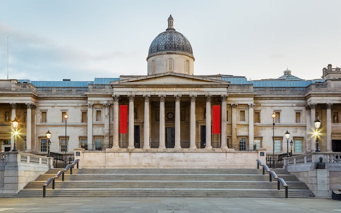National Gallery London facade with steps and lampposts in Trafalgar Square, UK.