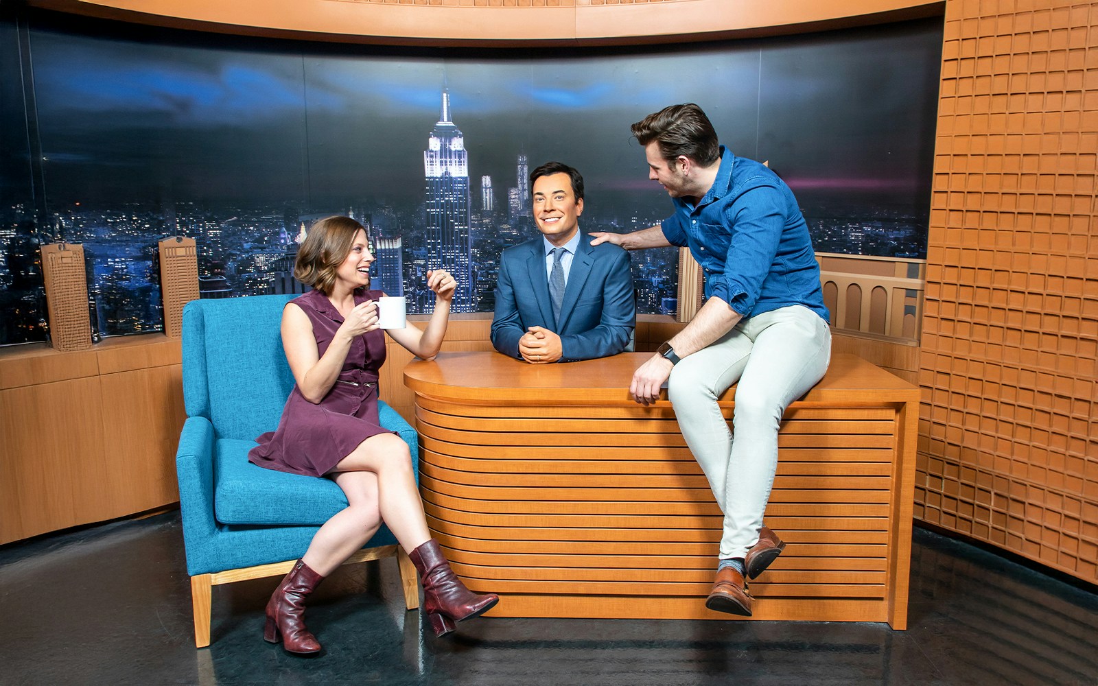 Guests interacting with Jimmy Fallon wax figure on The Tonight Show set at Madame Tussauds New York.