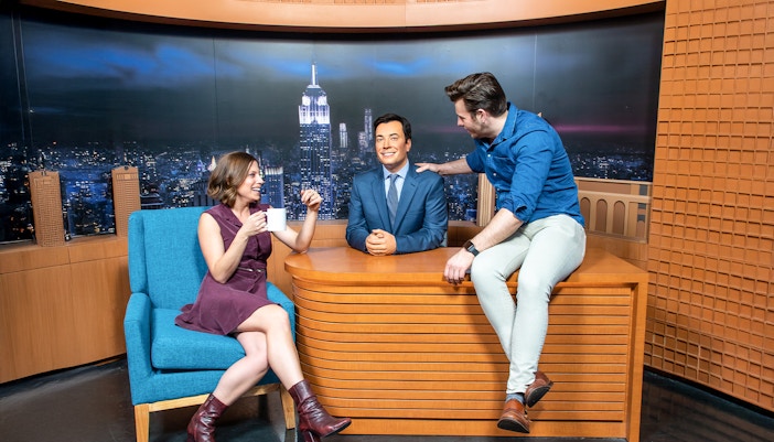 Guests interacting with Jimmy Fallon wax figure on The Tonight Show set at Madame Tussauds New York.
