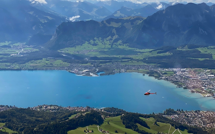 Helicopter flying over Stockhorn Mountain with view of lake and landscape from Bern-Belp Airport.