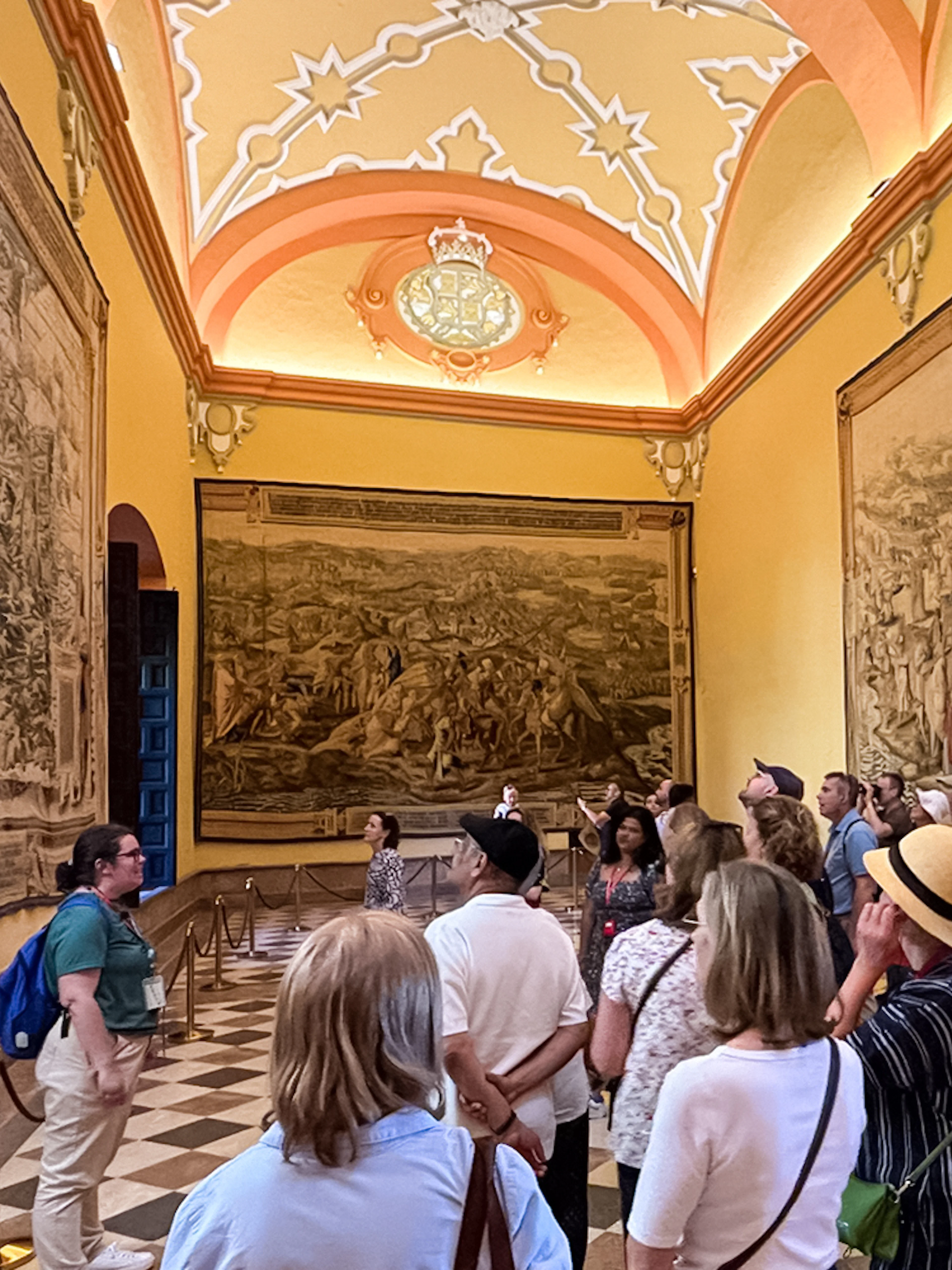 Tour group viewing tapestries in Alcázar of Seville during guided tour.