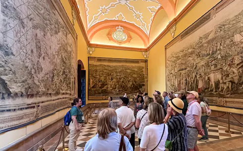 Tour group viewing tapestries in Alcázar of Seville during guided tour.