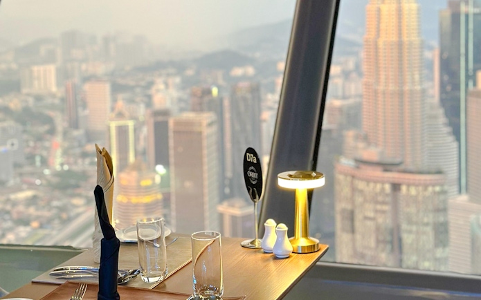 Dining table with cityscape view from ORBIT Revolving Dining in KL Tower, Kuala Lumpur.