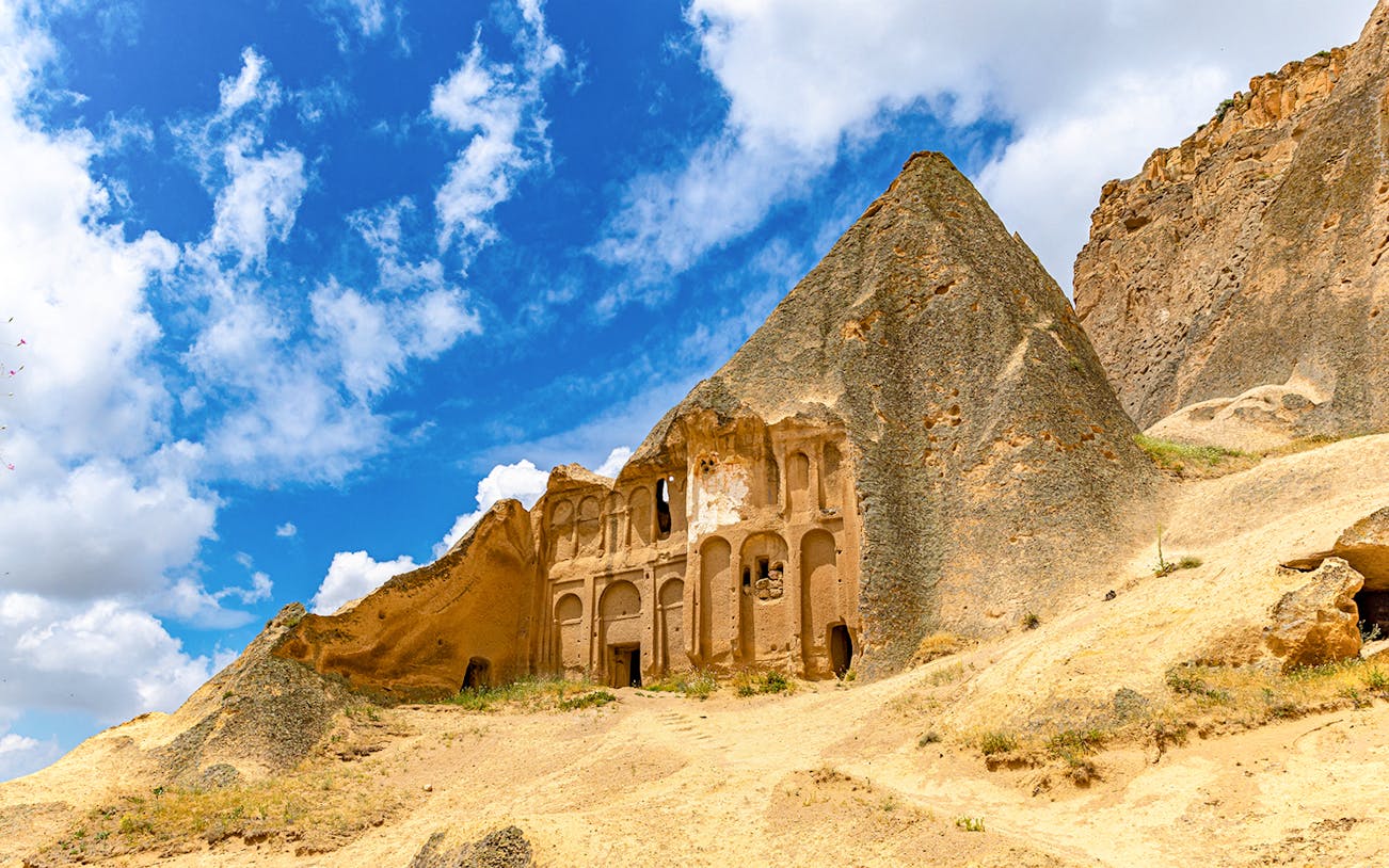 Rock-cut church in Ihlara Valley, Cappadocia, under a blue sky.