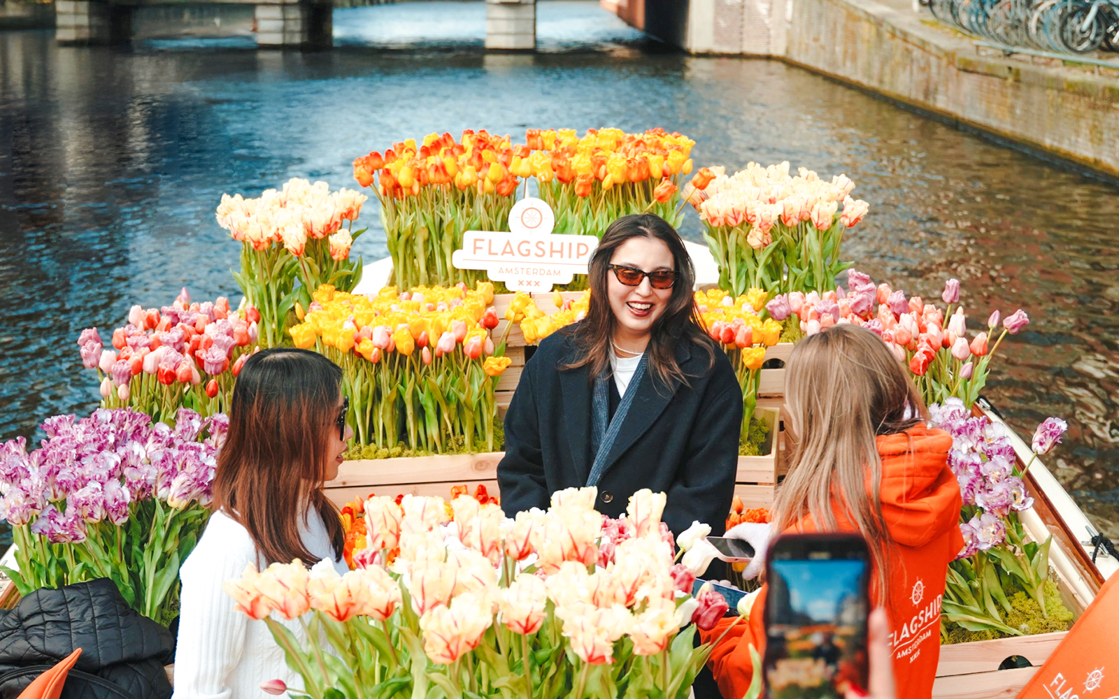 Guests enjoying tulip display on luxury cruise in Amsterdam canal.