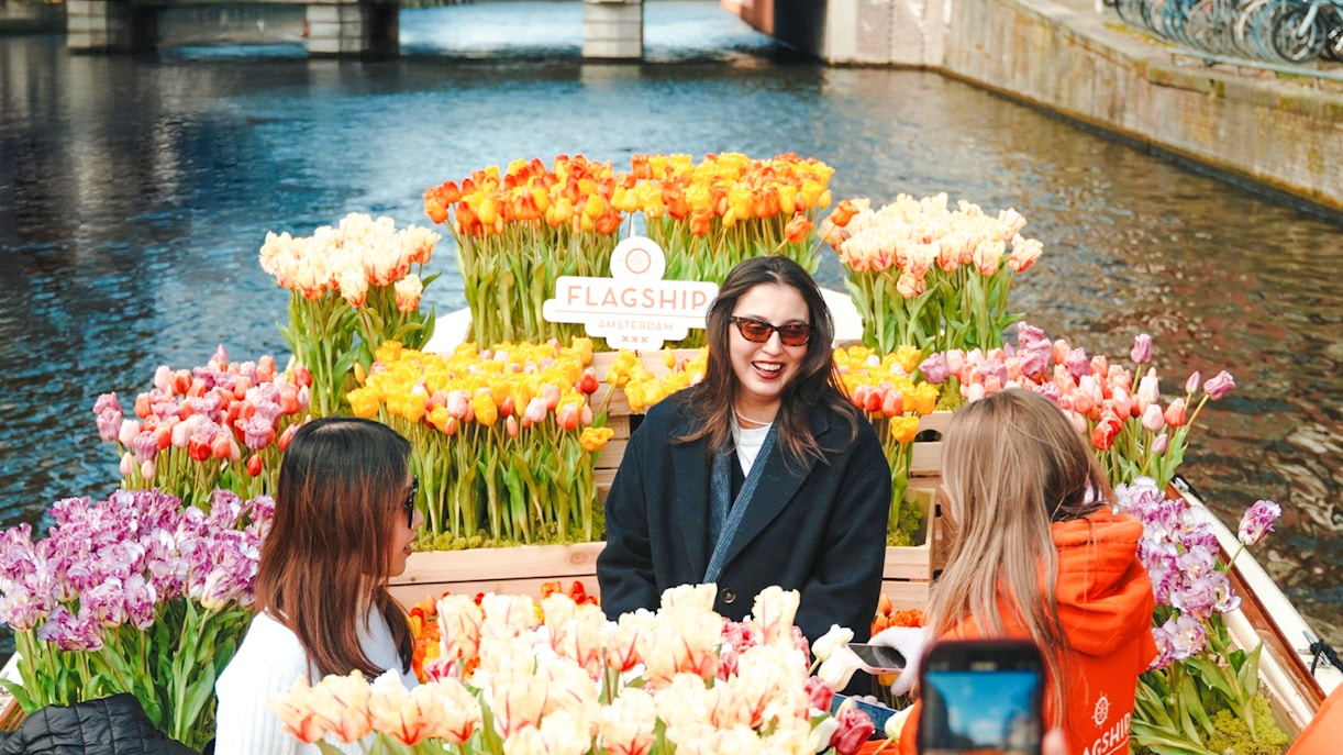 Guests enjoying tulip display on luxury cruise in Amsterdam canal.