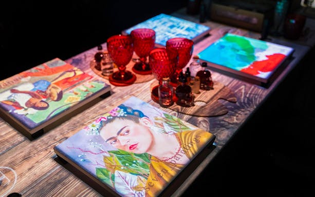 Paintings and red glassware on table at Seven Paintings Immersive Dining Show.