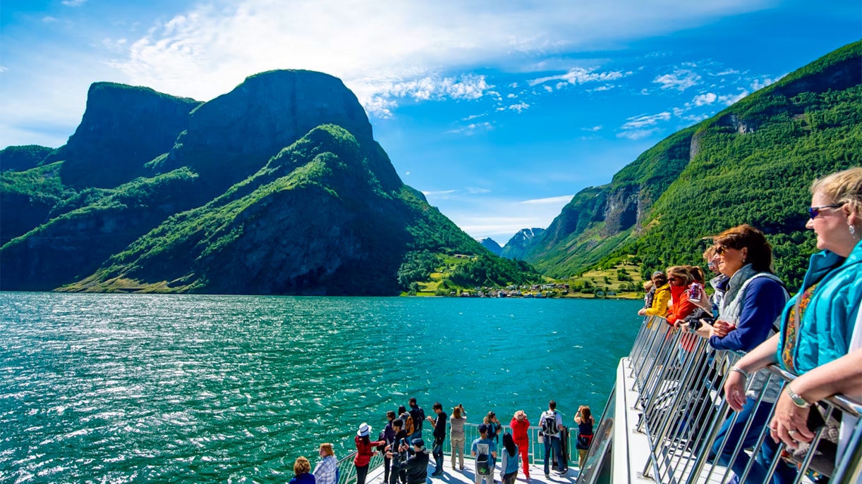 Tourists on a cruise ship deck enjoying views of Nærøyfjord's mountains and water.