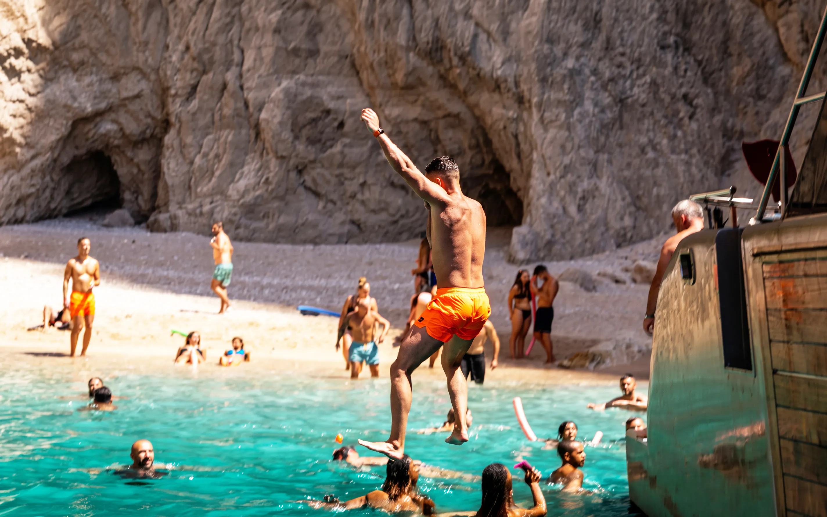 Tourist jumping from cruise ship into water at St. George Bay, Symi Island, Greece.
