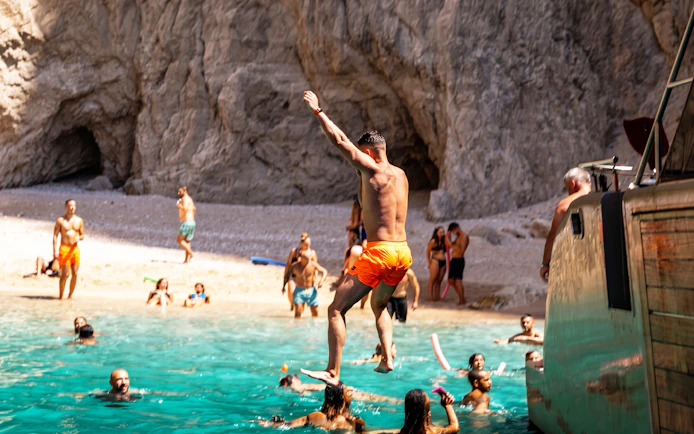 Tourist jumping from cruise ship into water at St. George Bay, Symi Island, Greece.