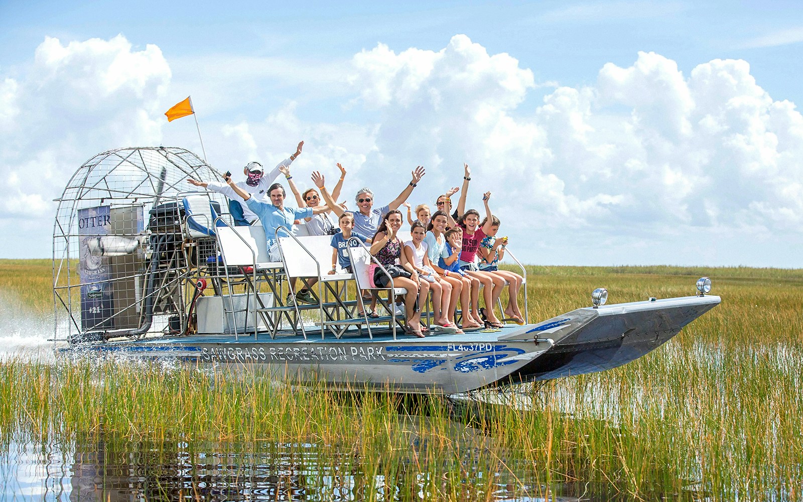 Group enjoying an airboat ride through the Everglades with grassy wetlands in the background.