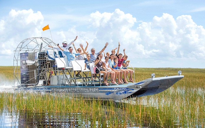 Group enjoying an airboat ride through the Everglades with grassy wetlands in the background.